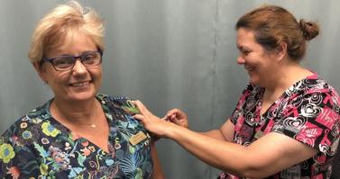 Innisfail Family Health Assistant Practice Manager – Annette Ah Shay (left) receives her COVID-19 vaccine from Registered Nurse Michelle McCarthy.jpg